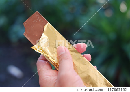 chocolate wrapped in gold paper on a natural background chocolate wrapped in gold paper on a natural background 117863162