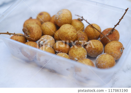 Longan fruit in plastic box on wooden table. Longan fruit in plastic box on wooden table. 117863190