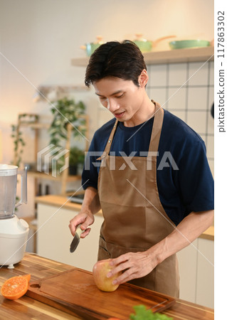 Handsome adult man wearing apron making healthy smoothie on kitchen counter Handsome adult man wearing apron making healthy smoothie on kitchen counter 117863302
