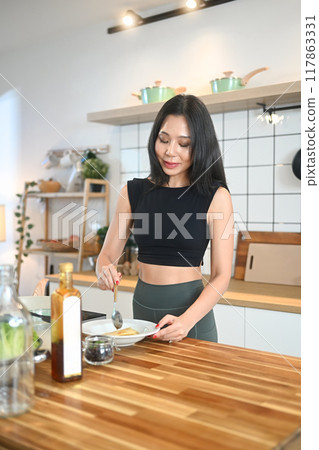Happy young woman preparing a healthy meal in kitchen. Health lifestyle and wellness concept Happy young woman preparing a healthy meal in kitchen. Health lifestyle and wellness concept 117863331