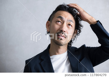 A man looking up and thinking about his scalp A man looking up and thinking about his scalp 117864270