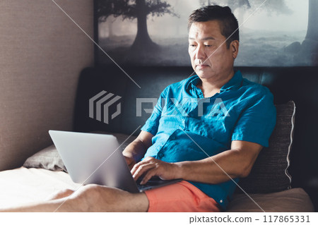 Man using a laptop in bed Man using a laptop in bed 117865331