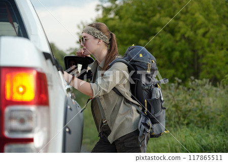 Young female hitchhiker with backpack Young female hitchhiker with backpack 117865511