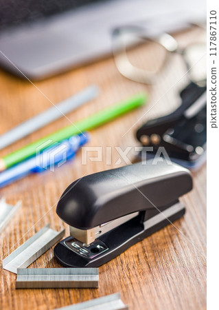 Black office stapler on wooden table. Black office stapler on wooden table. 117867110