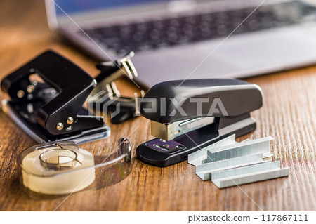 Office equipment. Stapler, staple remover, Scotch Tape Dispenser  and hole puncher on wooden table. 117867111