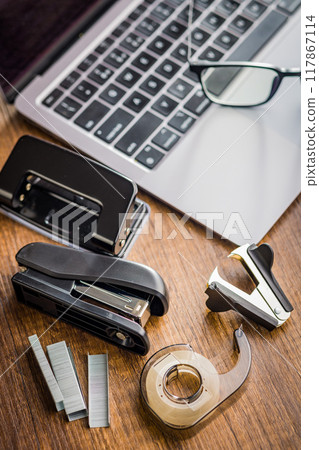 Office equipment. Stapler, staple remover, Scotch Tape Dispenser  and hole puncher on wooden table. 117867114