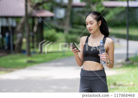Asian woman staying active in park during jogging break 117868468