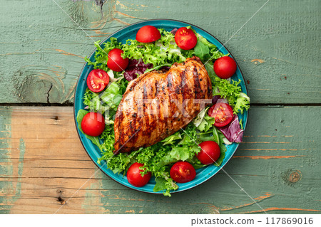Grilled chicken breast ( fillet ) with lattuce salad and cherry tomatoes . Top view Grilled chicken breast ( fillet ) with lattuce salad and cherry tomatoes . Top view 117869016