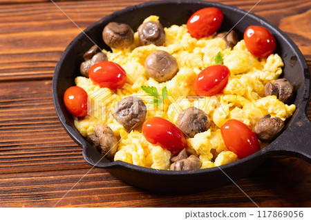 Healthy vegetarian breakfast . Scrambled eggs in pan with cherry tomatoes and parsley Healthy vegetarian breakfast . Scrambled eggs in pan with cherry tomatoes and parsley 117869056