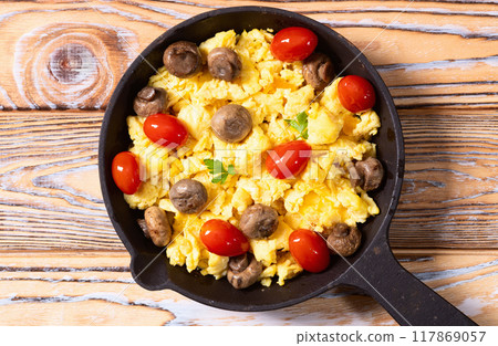 Healthy vegetarian breakfast . Scrambled eggs in pan with cherry tomatoes and parsley 117869057
