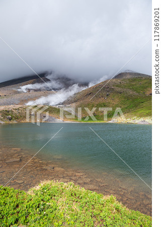 Emerald green pond of a volcano covered in clouds 117869201