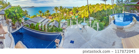 View over an infinity pool on a slope above a tropical beach 117872045