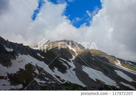Majestic Mountain Peak Piercing Through Clouds 117872207