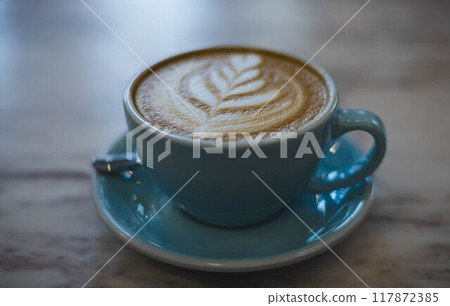 Delight in a beautifully crafted coffee with intricate latte art served in a cozy cafe ambiance on a tranquil morning Delight in a beautifully crafted coffee with intricate latte art served in a cozy cafe ambiance on a tranquil morning 117872385