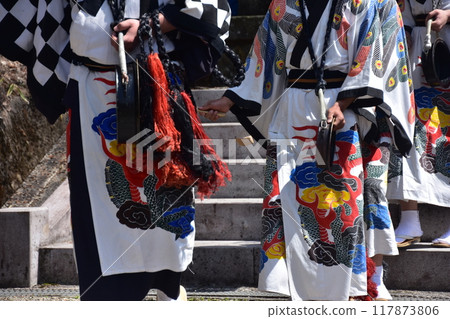 Takayama Festival in Spring, Takayama City, Gifu Prefecture, Japan. People ringing small bells called "Tokeiraku" wearing white costumes with pictures of birds. Takayama Festival in Spring, Takayama City, Gifu Prefecture, Japan. People ringing small bells called "Tokeiraku" wearing white costumes with pictures of birds. 117873806