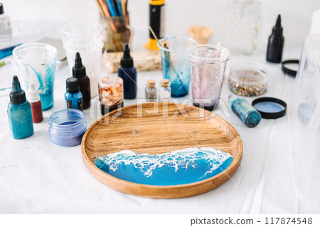 Creating stunning epoxy resin art with vibrant colors and textures for a coastal-themed serving tray at a DIY workshop Creating stunning epoxy resin art with vibrant colors and textures for a coastal-themed serving tray at a DIY workshop 117874548