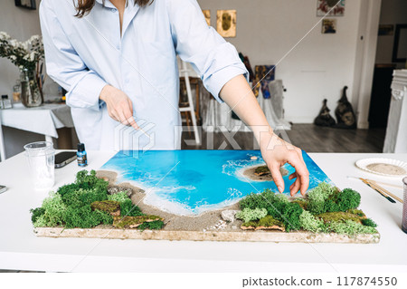 Hands crafting resin art coastal landscape, DIY project, handmade beach scene, creative home decor, nature-inspired artwork, epoxy resin hobby, artistic expression 117874550