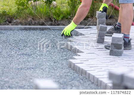 Worker building a new interlocking pavement from concrete paving, a new path building concept 117874822