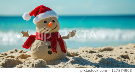Sand snowman is wearing a santa hat and scarf on a sunny beach 117874908