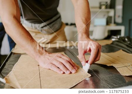 Unrecognizable male hands holding white chalk while drawing out stencil Unrecognizable male hands holding white chalk while drawing out stencil 117875233