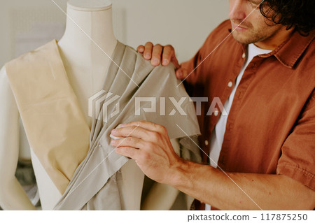 Medium close up of male famous tailor creating female clothing in atelier 117875250