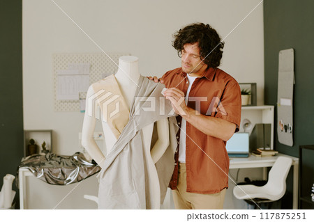 Curly haired tailor working on brand new dress in own atelier 117875251