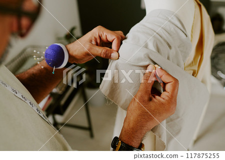 High angle shot of male hands holding gray cotton fabric while creating clothes High angle shot of male hands holding gray cotton fabric while creating clothes 117875255