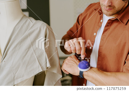 Unrecognizable tailor choosing needle to do darts on mannequin 117875259