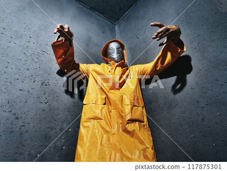 Giant scary man with duct tape face wrap in bright yellow raincoat looking down to camera 117875301