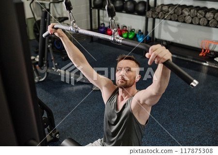 Man sitting on bench and preparing to use weight machine 117875308