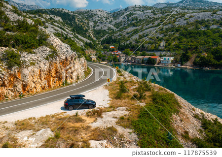 Car with a roof box stands on the cliff of lagoon, aerial view Car with a roof box stands on the cliff of lagoon, aerial view 117875539