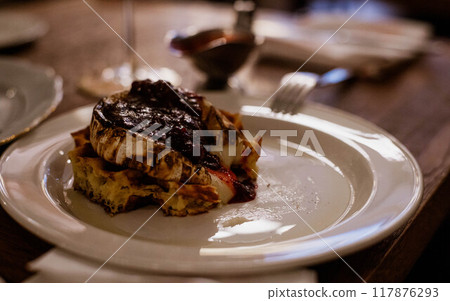 Deliciously crispy fried camembert cheese served with sweet fruit jam on a rustic wooden table 117876293