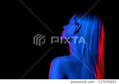 Woman with perfect long hair and bare shoulders against black studio background in neon light. Dedicated care and cosmetics. Back view 117876881