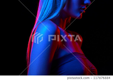 Woman with perfect long hair and bare shoulders against black studio background in neon light. Dedicated care and cosmetics. Cropped image 117876884