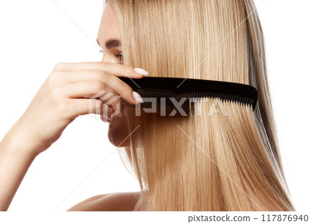 Stunning young woman with flawless blonde hair, brushing straight hair isolated on white studio background. Effective hair care and cosmetics. Stunning young woman with flawless blonde hair, brushing straight hair isolated on white studio background. Effective hair care and cosmetics. 117876940