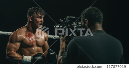 Cameraman closely filming tired and battered boxer after grueling match, capturing the raw emotion of the moment. Cameraman closely filming tired and battered boxer after grueling match, capturing the raw emotion of the moment. 117877019