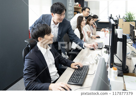 Six staff members working at a computer in an office Six staff members working at a computer in an office 117877379