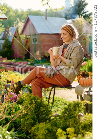 Female gardener having tea or coffee Female gardener having tea or coffee 117878322