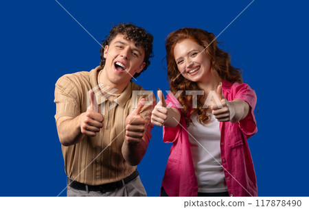 Positive woman and man with hand sign like, thumbs up gesture. Couple on blue Positive woman and man with hand sign like, thumbs up gesture. Couple on blue 117878490