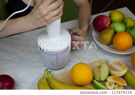 Sporty girl preparing milkshake in blender with fruits on background of table with ingredients for sports cocktail, healthy lifestyle and food with vitamins Sporty girl preparing milkshake in blender with fruits on background of table with ingredients for sports cocktail, healthy lifestyle and food with vitamins 117879159