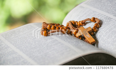 Dark brown wooden cross on an old open book symbolizing the spread of Jesus Christs love among Christians reflecting faith devotion and the importance of Christian teachings. 117880478