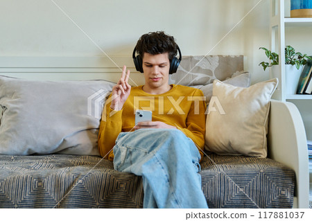 Young guy 19-20 years old in headphones using smartphone, talking on video call 117881037