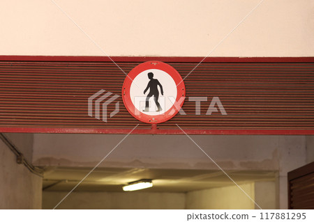 Prohibition sign. Pedestrian traffic is prohibited road sign, man in red circle on wall at entrance to underground parking lot at residential building at city. Restrict the movement of pedestrian. 117881295