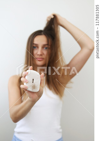 Hair loss problem. Worried young woman shows hairbrush with bunch of fallen hair after combing. Postpartum period, menstrual or endocrine disorder, hormonal disbalance, stress concept. Selective focus Hair loss problem. Worried young woman shows hairbrush with bunch of fallen hair after combing. Postpartum period, menstrual or endocrine disorder, hormonal disbalance, stress concept. Selective focus 117881305