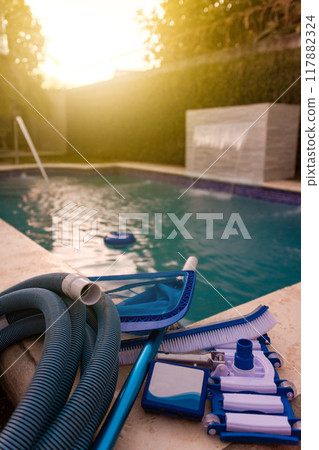 Pool cleaning and maintenance kit, Cleaning and maintenance tools on the edge of the pool. vacuum cleaner, ph test, skimmer and pool sweeper 117882324