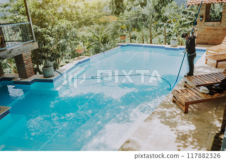 Pool maintenance and cleaning with vacuum suction hose. Worker cleaning a beautiful swimming pool with vacuum suction hose Pool maintenance and cleaning with vacuum suction hose. Worker cleaning a beautiful swimming pool with vacuum suction hose 117882326