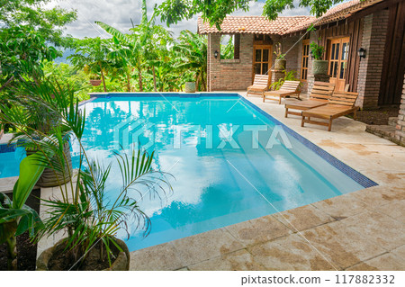 Beautiful swimming pool surrounded by nature. A crystal clear swimming pool surrounded by trees. Concept of home pool designs Beautiful swimming pool surrounded by nature. A crystal clear swimming pool surrounded by trees. Concept of home pool designs 117882332