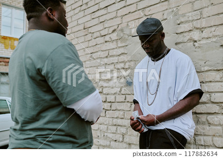 Man leaning on old garage wall while counting money, customer waiting for him calmly 117882634