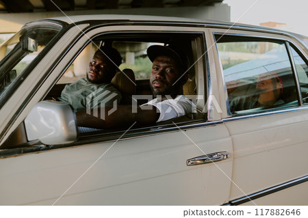 Brutal and tough men sitting in old car and looking directly at camera Brutal and tough men sitting in old car and looking directly at camera 117882646
