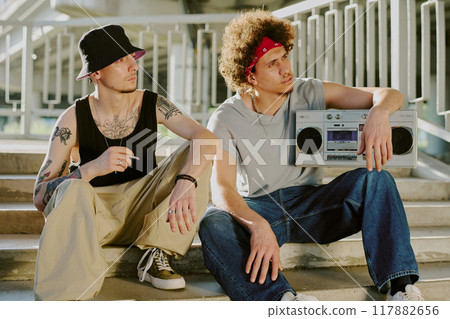 Biracial friends hanging out together and listening to music via retro tape recorder 117882656